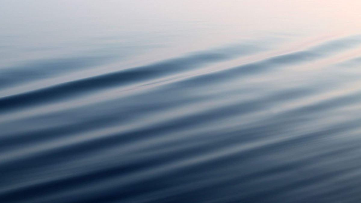 Calm water surface with soft, diagonal ripples and gentle reflections, creating a serene and minimalistic abstract pattern.