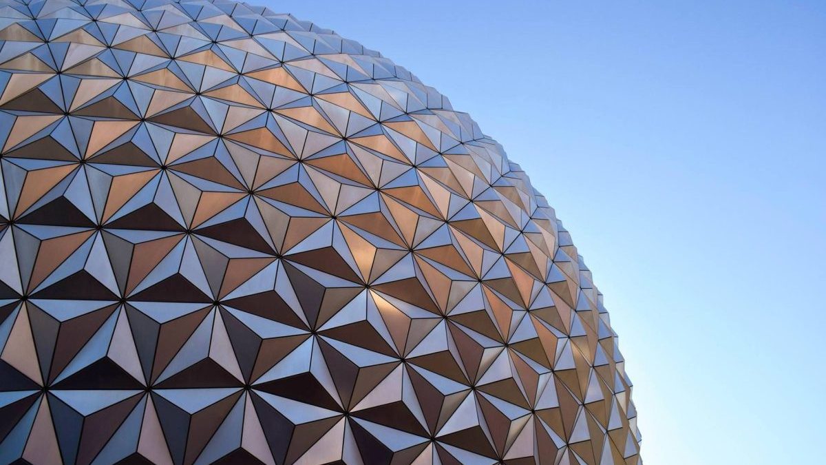 Close-up view of a large geodesic sphere with triangular panels against a clear blue sky.