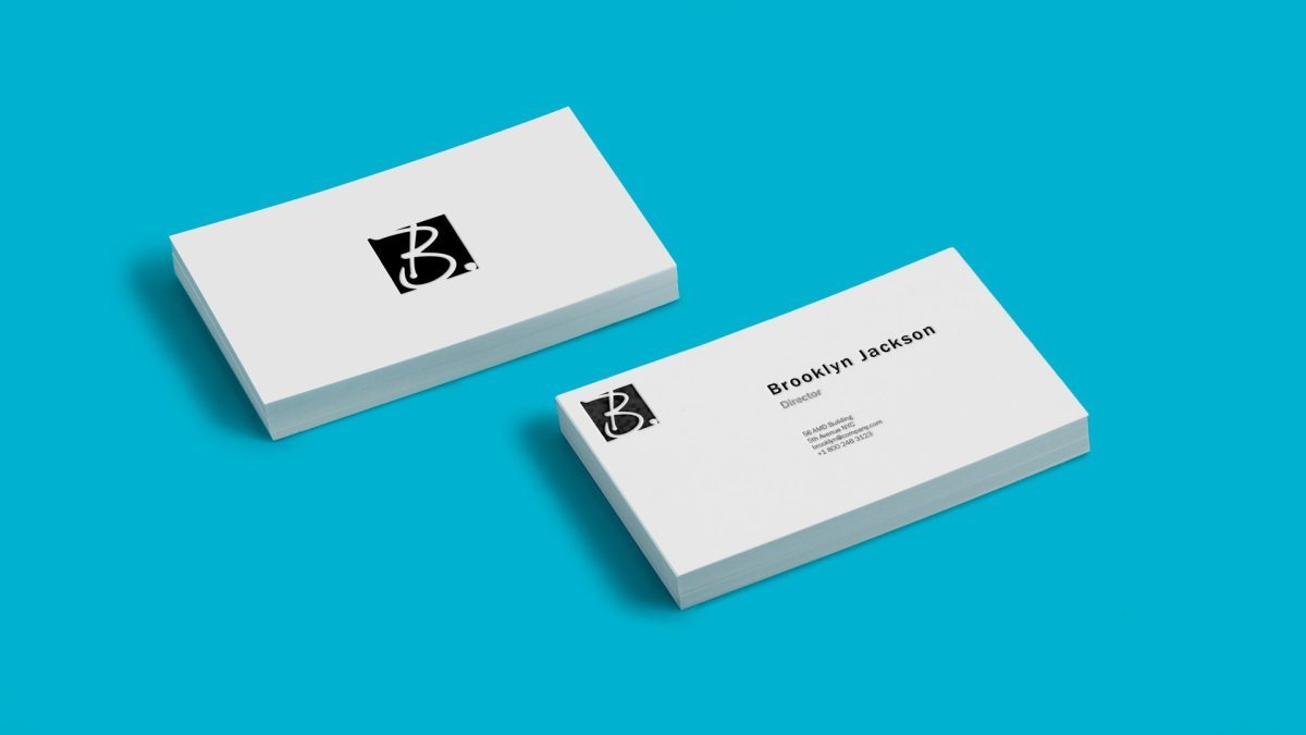 Two stacks of white business cards on a blue background; one stack shows a black logo, the other displays contact information for Brooklyn Jackson.